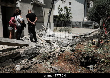 Ashkelon, Israele. Il 5 maggio, 2019. Una famiglia ispeziona i danni al loro domicilio riddled con fori di shrapnel. Uno dei più di 600 razzi lanciati in Israele dalla controllata di Hamas nella Striscia di Gaza in meno di 48 ore sbarcati nel cortile, uccidendo il prossimo Moshe Agadi e danneggiare due case. Credito: Nir Alon/Alamy Live News Foto Stock