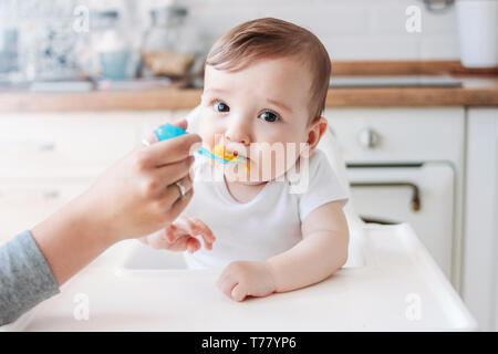 Affascinante piccolo bimbo 6-8 mesi prima di mangiare cibo da zucca cucchiaio a casa Foto Stock