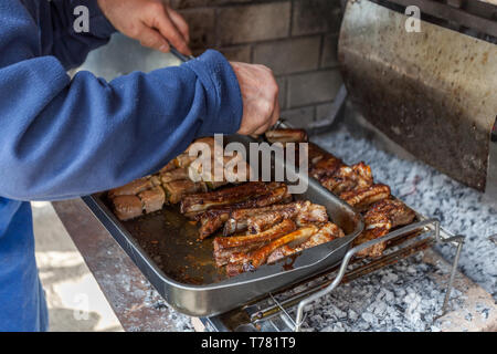 La cottura della carne di maiale alla griglia in un caminetto Foto Stock