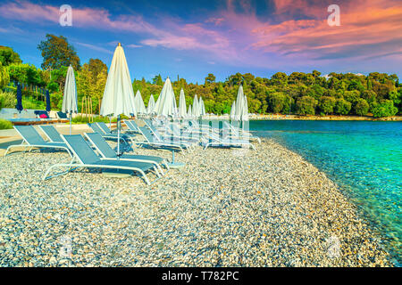 Bellissimo viaggio e destinazione di vacanza. Pittoresca spiaggia di ghiaia e il mare. Sedie a sdraio e ombrelloni da spiaggia al tramonto sulla spiaggia, Rovigno, IST Foto Stock