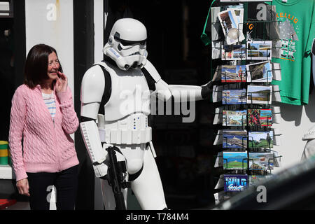 Un membro della '501Legion Irlanda Garrison' vestito come un Stormtrooper guarda le cartoline postali sulle strade di Portmagee, Kerry, durante il Maggio 4 Festival, dove le scene di Star Wars sono state filmate. Foto Stock