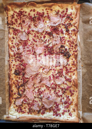 Immagine della tradizionale Tarte flambee con creme fraiche formaggio, cipolla e pancetta. Vista dall'alto in basso, Piana, laici close up Foto Stock