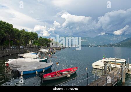 Una vista sul porto di Lenno sul Lago di Como verso Bellagio a distanza con le montagne al di là e al di sotto di un moody cielo grigio Foto Stock