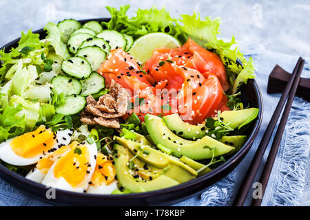 Salmone poke ciotola servita con avocado, uova, cetrioli e verdi Foto Stock