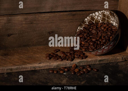 I chicchi di caffè spargimento su una scatola di legno Foto Stock