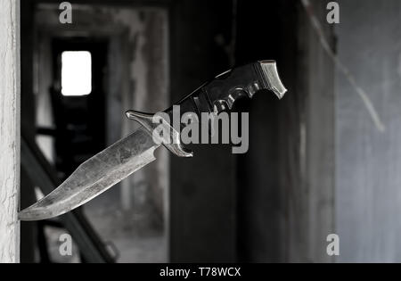 Terribile combattimento coltello vecchio bloccata nel vano della porta sullo sfondo del corridoio in rovina della vecchia casa abbandonata Foto Stock
