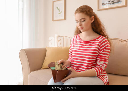 Giovane donna mettendo dollar banconota in portafoglio all'interno. Risparmio di denaro concept Foto Stock