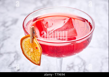 Cocktail di rosso con un grande pezzo di ghiaccio decorato con secchi fetta d'arancia. Copia dello spazio. Close up Foto Stock