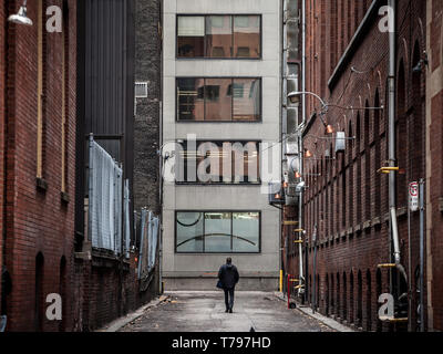 L'uomo waliing da soli in un dead end street presso il fondo di grattacieli nel centro cittadino di Toronto, Ontario, Canada, nel CBD. Toronto è una grande Nord America Foto Stock