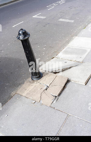Rotture di pavimentazione in pericolo di inciampare e di metallo bollard Foto Stock