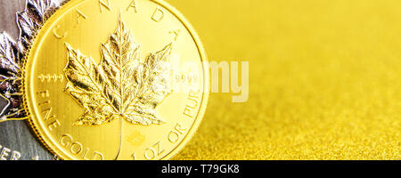 Primo piano della silver e golden canadian maple leaf uno oncia di monete su sfondo dorato posto sul lato sinistro Foto Stock