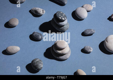 Enrtainment per bambini con pietre e rocce. Montessori dei giochi di bilanciamento, ciottoli isolati su sfondo blu Foto Stock