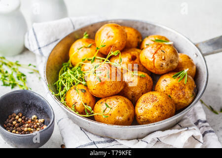 Patate al forno in una padella in ghisa, sfondo bianco. Foto Stock