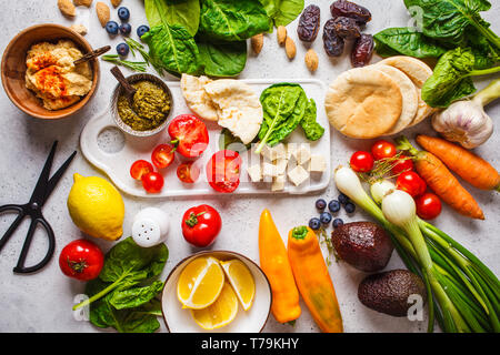 Una sana alimentazione vegetariana sfondo. Verdure, hummus, pesto e frutti. Foto Stock