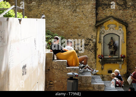 Turisti che si siedono sui passi dalla statua di San Giorgio santuario al Castelo de Sao Jorge Lisbona Castello di Lisbona Portogallo Europa KATHY DEWITT Foto Stock