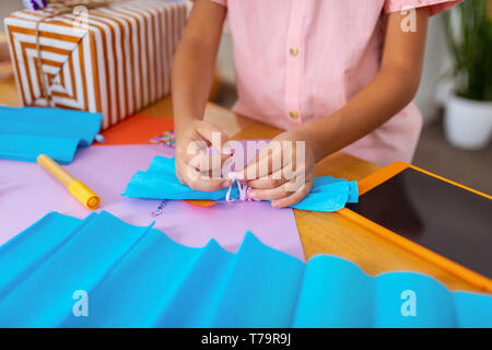 Ragazzo che prua. Close up schoolboy indossando maglia rosa la preparazione di carta archetto per la presente casella Foto Stock