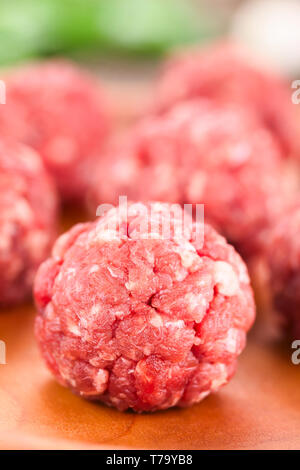 Crudo fresco polpette di carne sul piatto di legno (messa a fuoco selettiva, messa a fuoco sulla parte anteriore della prima polpetta) Foto Stock