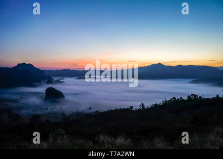 Sunrise al mattino dietro la montagna e la nebbia al di sotto di Phu Langka, Phayao provincia a nord della Thailandia. Foto Stock