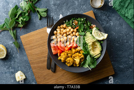 Ciotola di Buddha. Sana vegetariana alimento equilibrato. -, Aloo Gobi, ceci, pomodoro, avocado, tabule insalata e spinaci Foto Stock