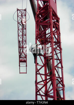 Lavoratore a lavorare su una gru Foto Stock