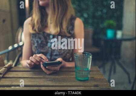 Una giovane donna con il suo smartphone in un ristorante Foto Stock