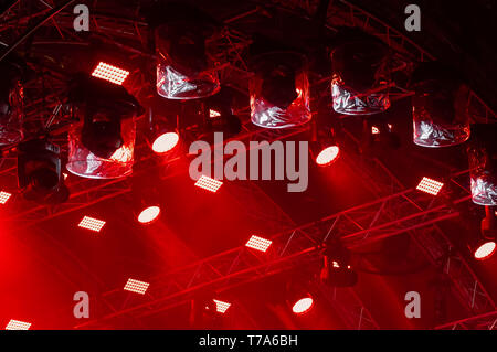 Concerto colorata illuminazione. Lanterne rosse e faretti in un concerto. I raggi di luce di illuminazione di concerto su uno sfondo scuro sopra il proiettore scre Foto Stock