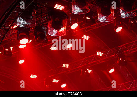 Concerto colorata illuminazione. Lanterne rosse e faretti in un concerto. I raggi di luce di illuminazione di concerto su uno sfondo scuro sopra il proiettore scre Foto Stock