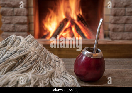 Coppa tradizionale per il compagno di bere e di lana sciarpa, vicino al caminetto, in country house, hygge, casa dolce casa. Foto Stock