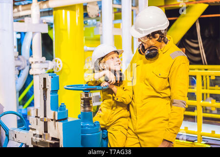 Il giovane e un ragazzino sono entrambi in un giallo uniforme di lavoro, occhiali e casco in un ambiente industriale, piattaforma di olio o gas liquefatto impianto Foto Stock