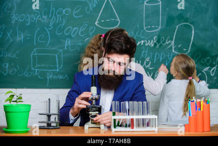 Spiegare la biologia per i bambini. Biologia svolge ruolo nella comprensione delle complesse forme di vita. Insegnante della Scuola di biologia. Uomo Barbuto maestro lavora con microscopio e provette per la prova in biologia classe. Foto Stock