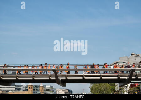 Scuola bambini indossare hi-vis giacche attraversando il Millennium Bridge sul fiume Tamigi a Londra, sul loro modo di visitare la Tate Modern Gallery Foto Stock