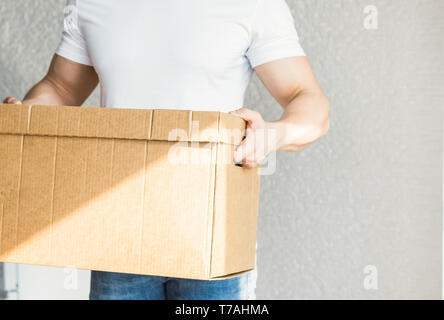 Consegna forte e muscoloso uomo caricando le scatole di cartone per la movimentazione di un appartamento. il lavoratore professionale di trasporto, caricatori maschio in tuta. fre Foto Stock