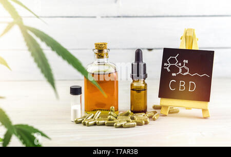 Cannabidiolo oli CBD, capsule e cristalli di isolare con piccola lavagna con parola CBD e struttura chimica su uno sfondo di legno Foto Stock