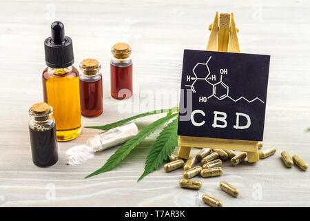 Full Spectrum cannabidiolo oli CBD, capsule e cristalli di isolare con piccola lavagna con parola CBD e struttura chimica su uno sfondo di legno Foto Stock