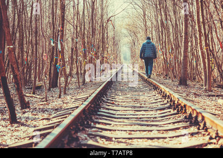 Un uomo cammina lungo le rotaie della vecchia ferrovia nella foresta Foto Stock