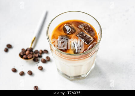 Ice caffè con latte in un bicchiere sul grigio brillante background in calcestruzzo. Sana energia boost e freddo rinfrescante drink estivo Foto Stock