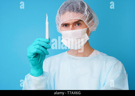 Chirurgo sterili in uniforme blu, guanti medicali e maschera Foto Stock