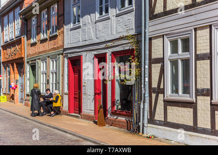 La gente seduta al sole di fronte alle loro case colorate in Schwerin, Germania Foto Stock