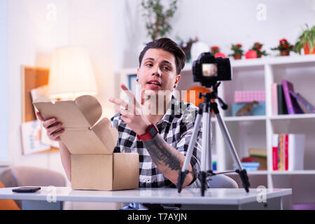 Comunicativi dai capelli scuri ragazzo in camicia a scacchi unboxing package Foto Stock