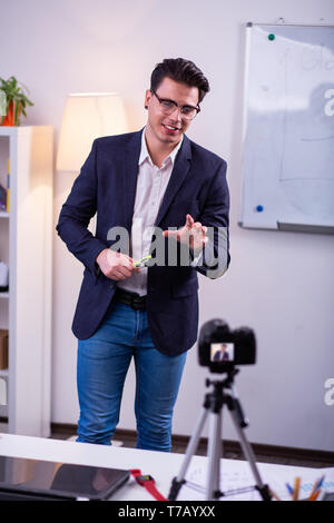 Sicuro di sé uomo bello in abito elegante lavorando su telecamera Foto Stock