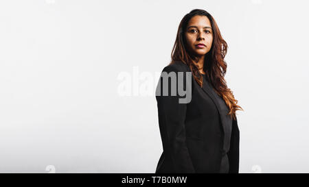 Vista laterale di una giovane imprenditrice isolati su sfondo bianco. Ritratto di una donna in business formale rivestimento avente dorato marrone capelli. Foto Stock