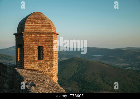 Piccola torre di avvistamento fatta di mattoni sulla scogliera con paesaggio collinare sul tramonto a Marvao. Un borgo medievale arroccato su una rupe in Portogallo. Foto Stock