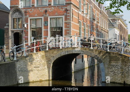 DELFT, Paesi Bassi - 22 Aprile 2019: le facciate storiche situate lungo Oude Delft Canal, con ponte Breestraat in primo piano Foto Stock