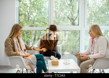 Coppia giovane avente incomprensioni durante la consultazione psicologica con senior psicologo femmina in ufficio Foto Stock