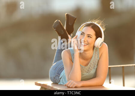 Corpo pieno ritratto di una ragazza felice ascoltando musica guardando a lato Foto Stock