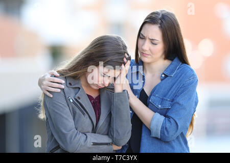 Preoccupato donna consolante il suo triste amico che si lamenta per la strada Foto Stock