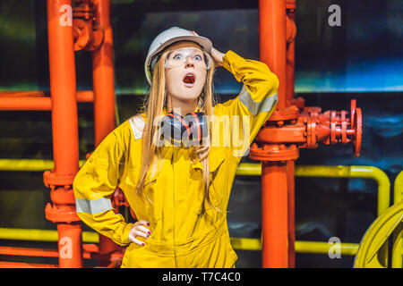 Giovane donna in un giallo uniforme di lavoro, occhiali e casco in ambiente industriale,piattaforma di olio o gas liquefatto impianto Foto Stock