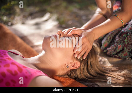 Donna massaggiatrice si applica la sua abilità di massaggio sul suo client sull'erba. Foto Stock