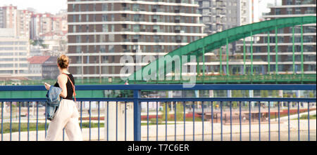 Belgrado, Serbia - Aprile 26, 2019: giovane donna camminare sopra il ponte della città con vista su Belgrado Waterfront project Foto Stock