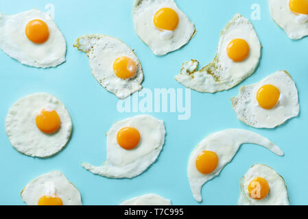 Uova fritte o uova strapazzate pattern su sfondo blu. Cucina creativa del concetto. Vista superiore Foto Stock